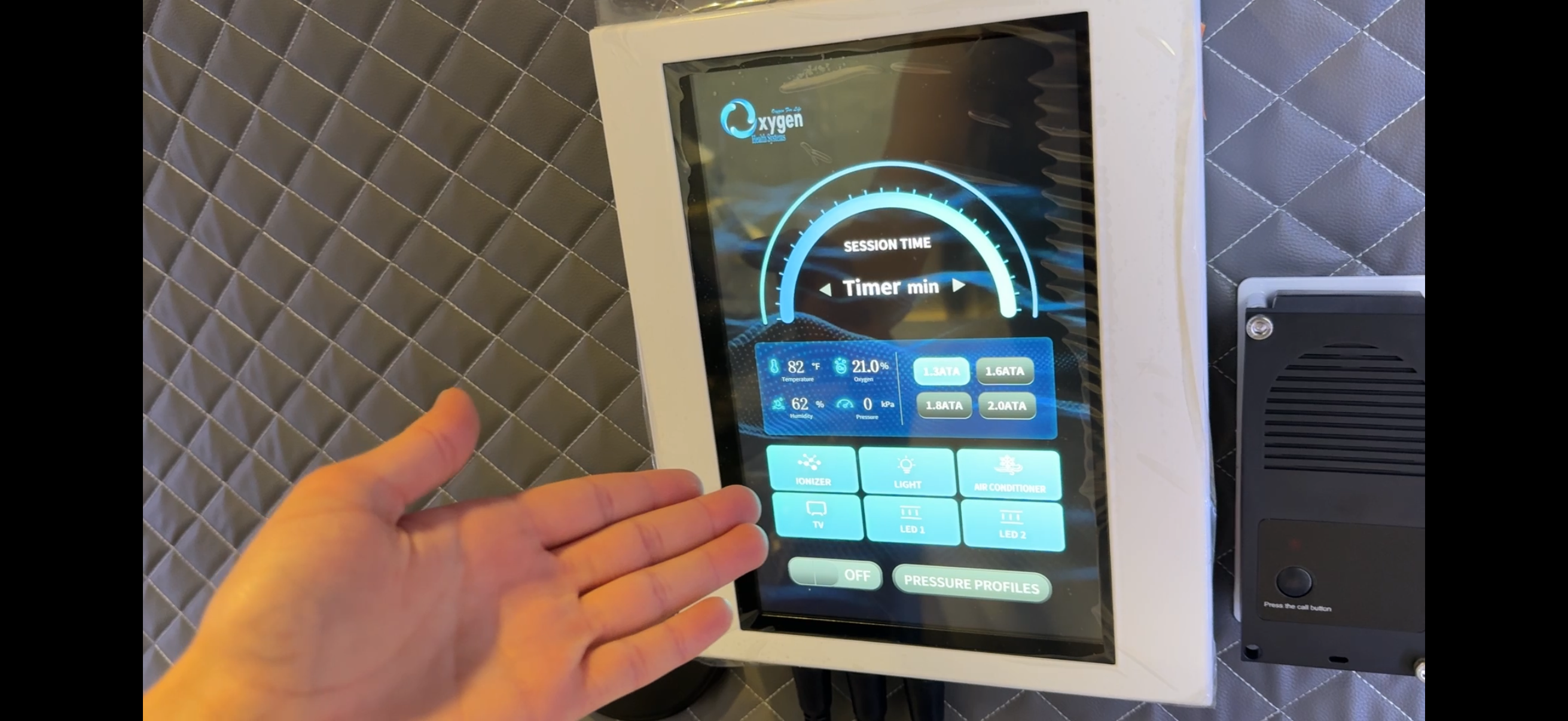 Intuitive high-definition internal touchscreen user interface mounted inside the chamber — showing session timer, real-time temperature, oxygen, humidity and pressure readouts, and chamber controls