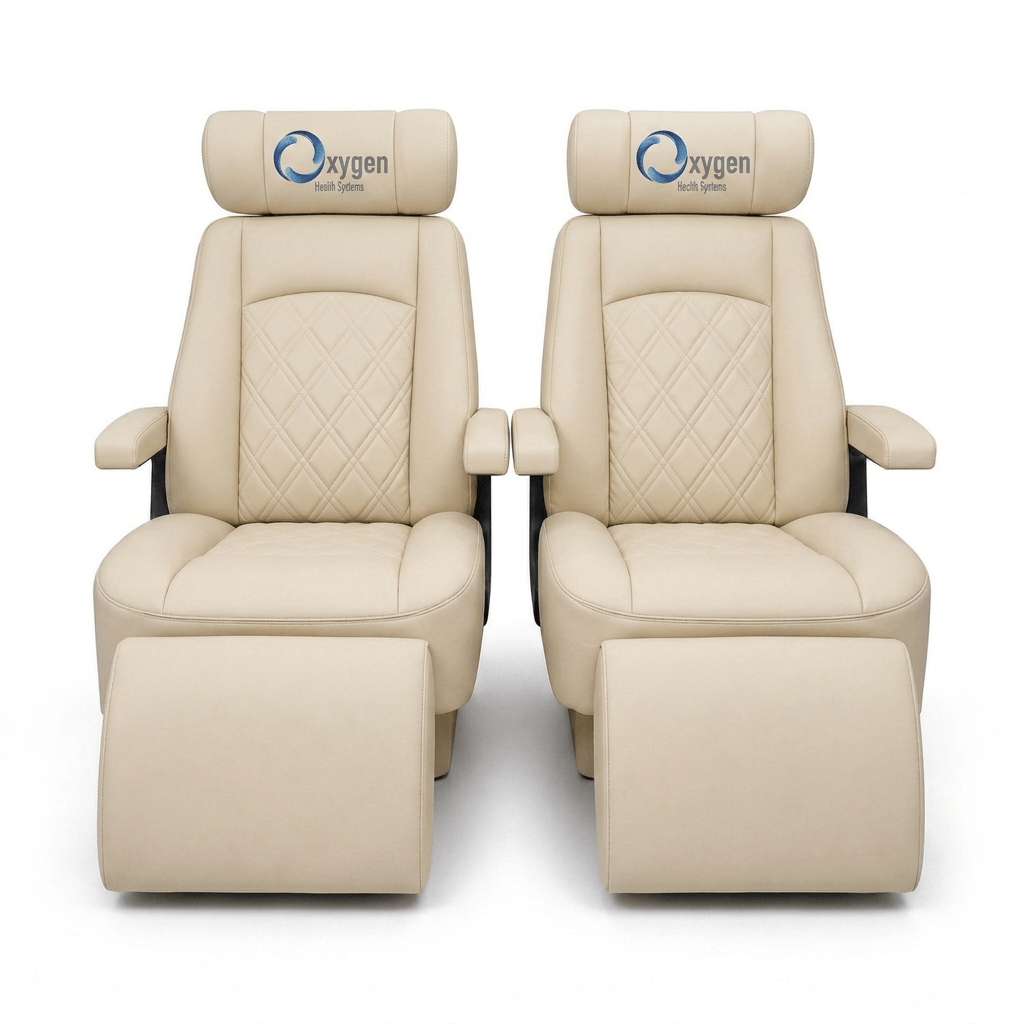 Two cream quilted leather Oxygen Health Systems captain's chairs with diamond-stitched backrests, embroidered logo headrests, padded armrests, and extended footrests