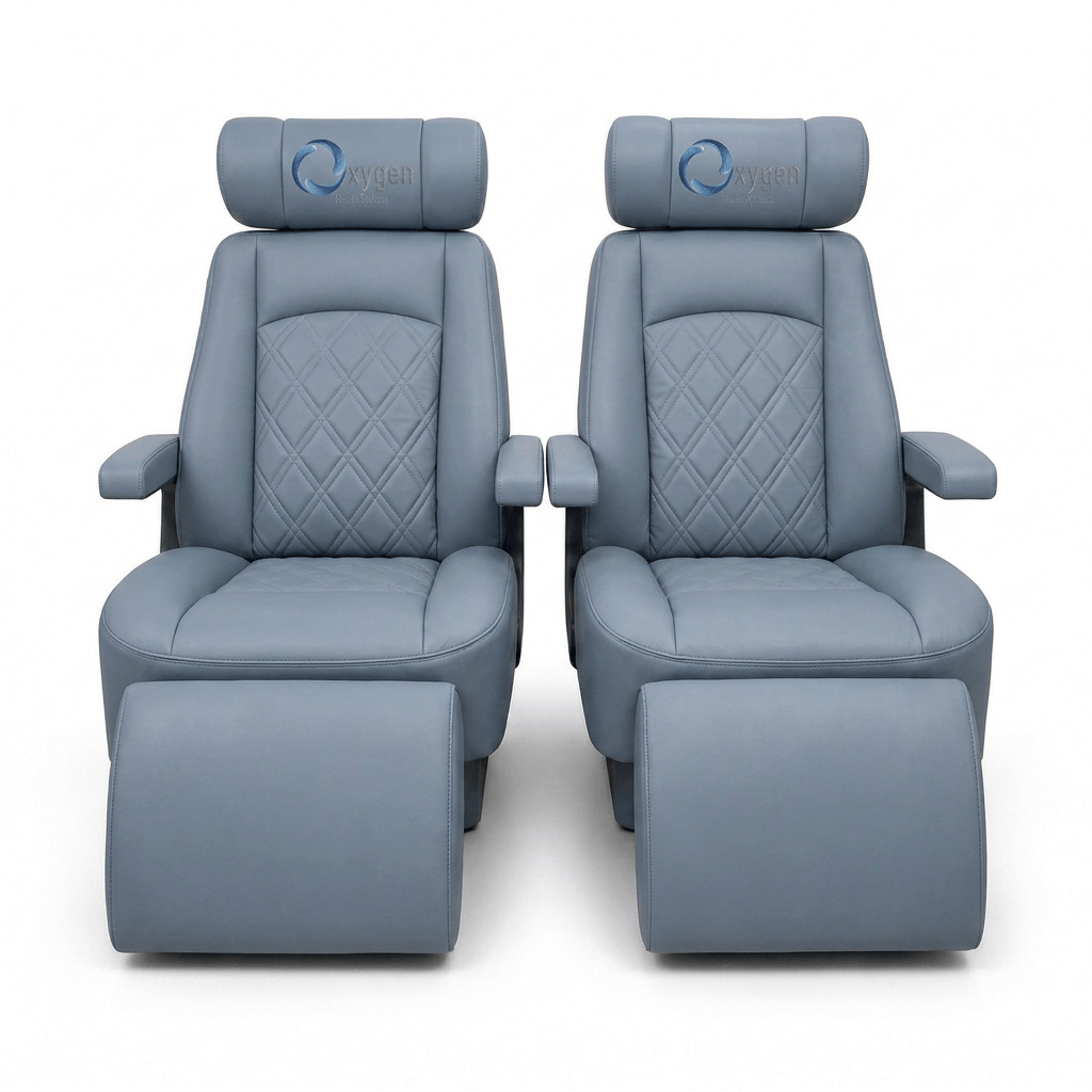 Two powder gray quilted leather Oxygen Health Systems captain's chairs with diamond-stitched backrests, embroidered logo headrests, padded armrests, and extended footrests