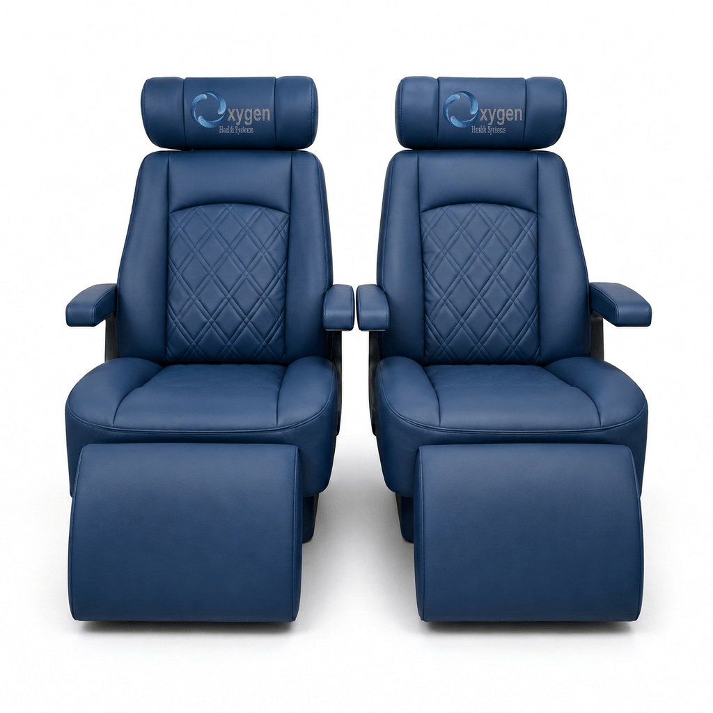 Two navy blue quilted leather Oxygen Health Systems captain's chairs with diamond-stitched backrests, embroidered logo headrests, padded armrests, and extended footrests